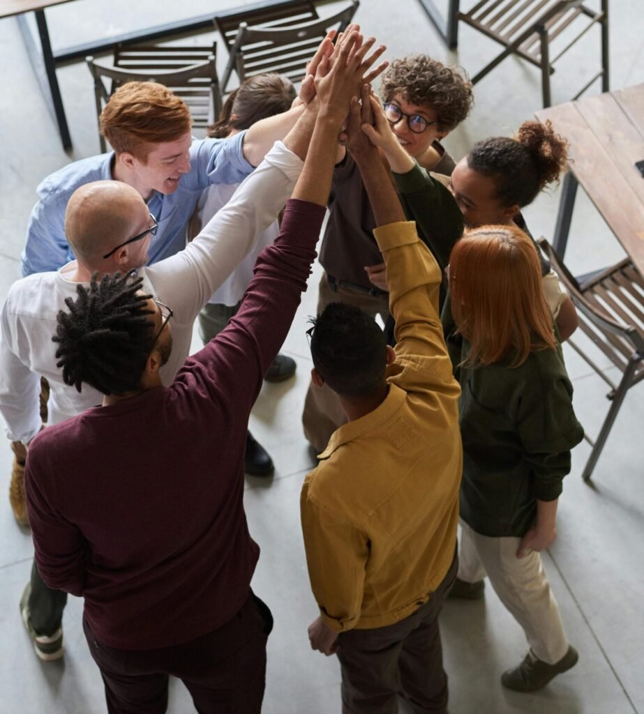 Team members of various backgrounds gathered together and joining hands in a gesture of inclusivity